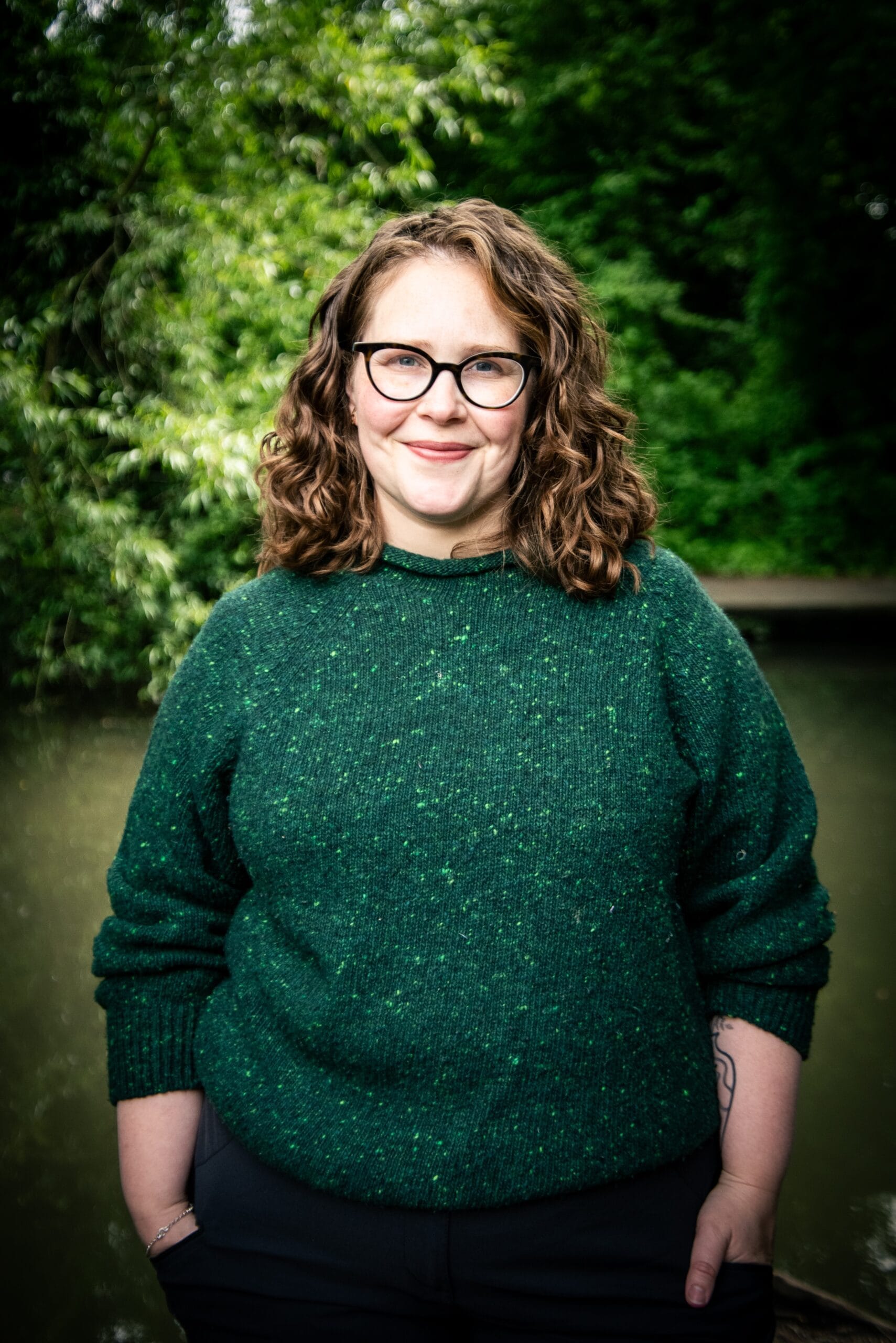 Annabell Webb Outdoor Arts Psychologist Annabell has fair skin, brown curly hair and glasses. She stands facing the camera with a closed mouth smile and a kind expression. She is wearing an emerald green knitted jumper.